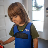 Child wearing a blue and black weighted vest with a visible brand logo indoors.